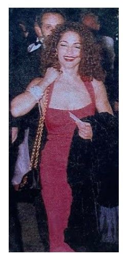 Estefan, Gloria / Smiling, in Red Dress, Holding Bag and Coat / 1992