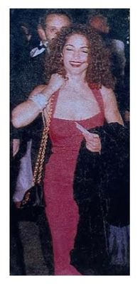Estefan, Gloria / Smiling, in Red Dress, Holding Bag and Coat / 1992