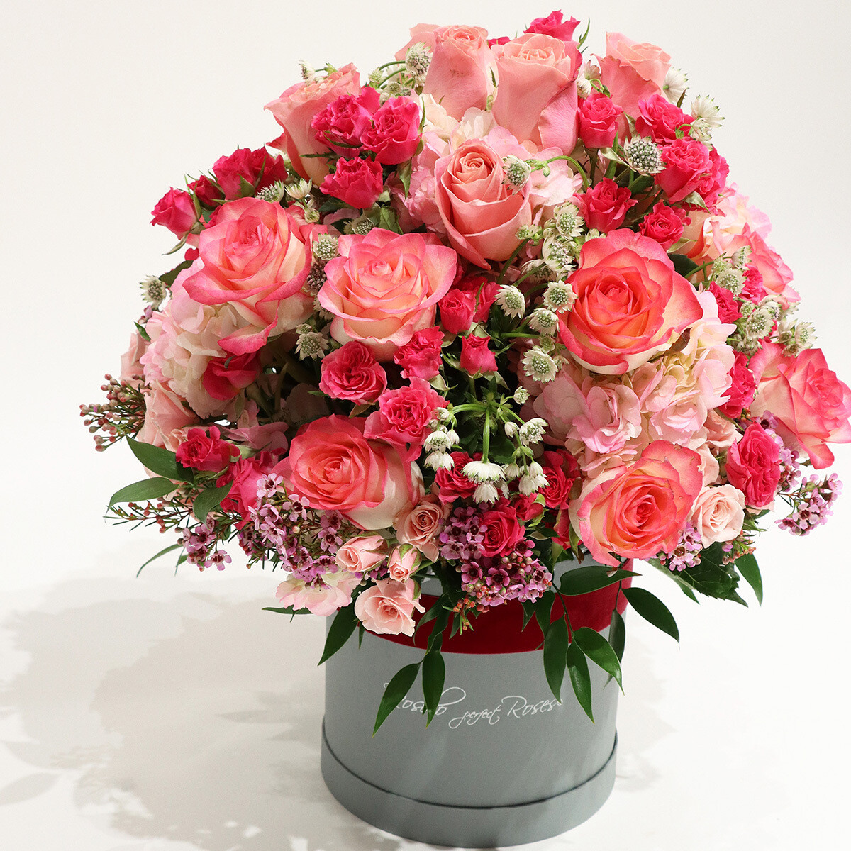 Roses, roses branchues et hortensias dans une belle boîte