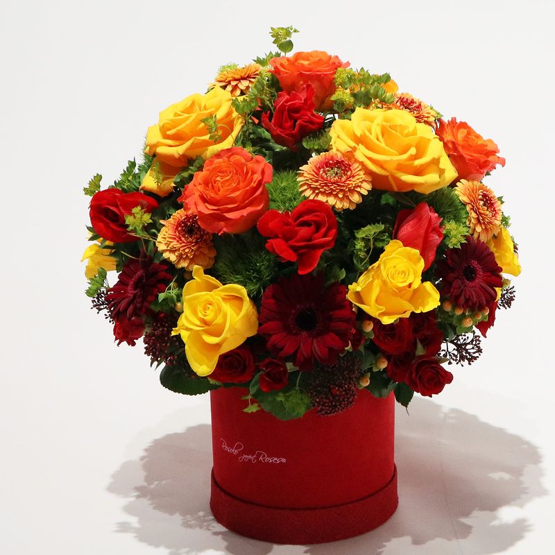 Composition lumineuse avec des roses et des fleurs de saison dans une belle boite Rosolo