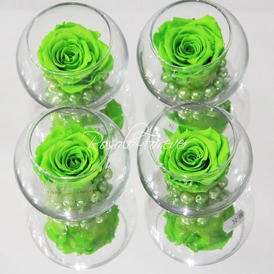 Une rose stabilisée en vert, avec perles décoratives dans un verre