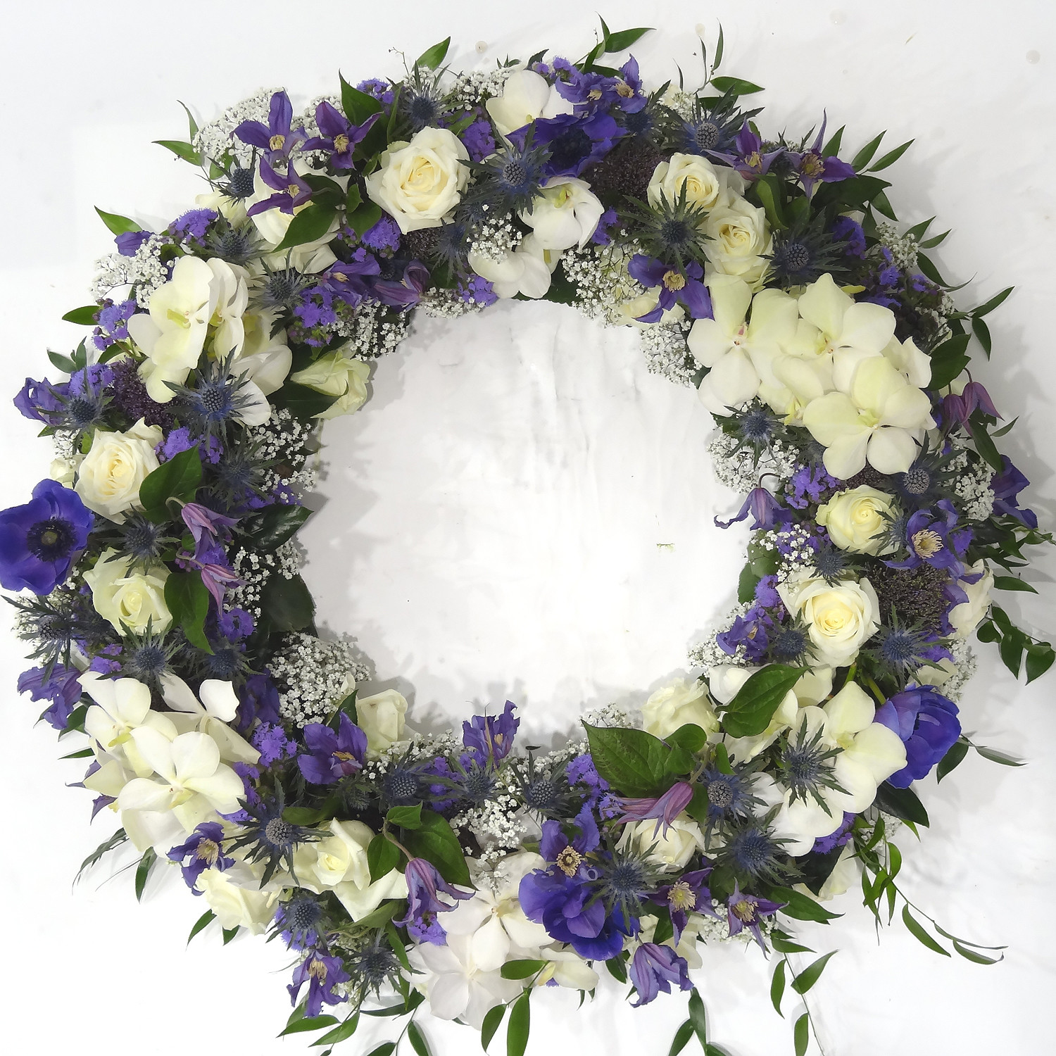 Couronne avec roses, orchidées et fleurs de saison en bleu et blanc