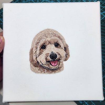Machine-stitched embroidered portrait of a dog on a canvas frame, with fine thread details and natural colors.