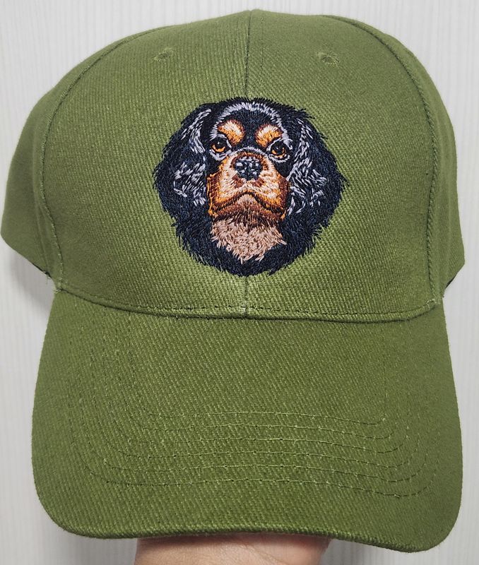 Olive green baseball cap featuring a detailed custom embroidered head of a black and tan Cavalier King Charles Spaniel dog.