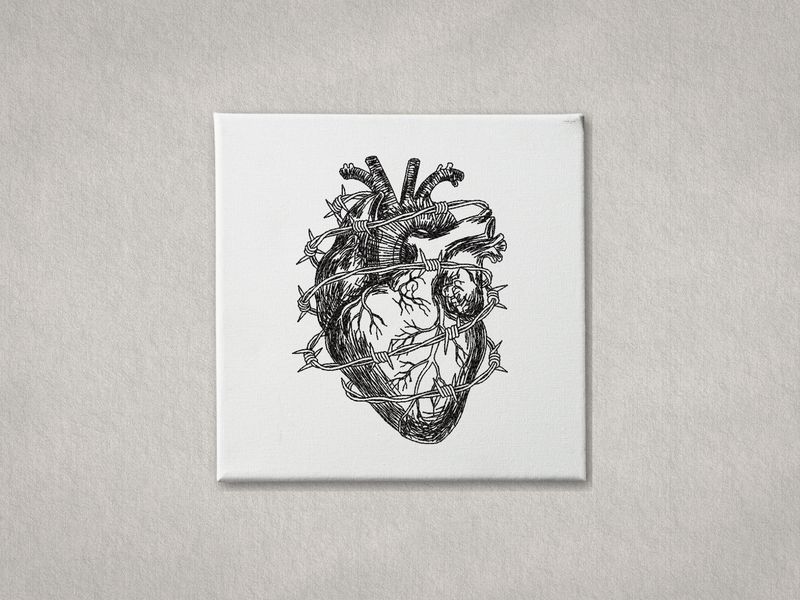 Black machine-embroidered anatomical heart with barbed wire on a white gallery-wrapped canvas. Minimalist grey background.