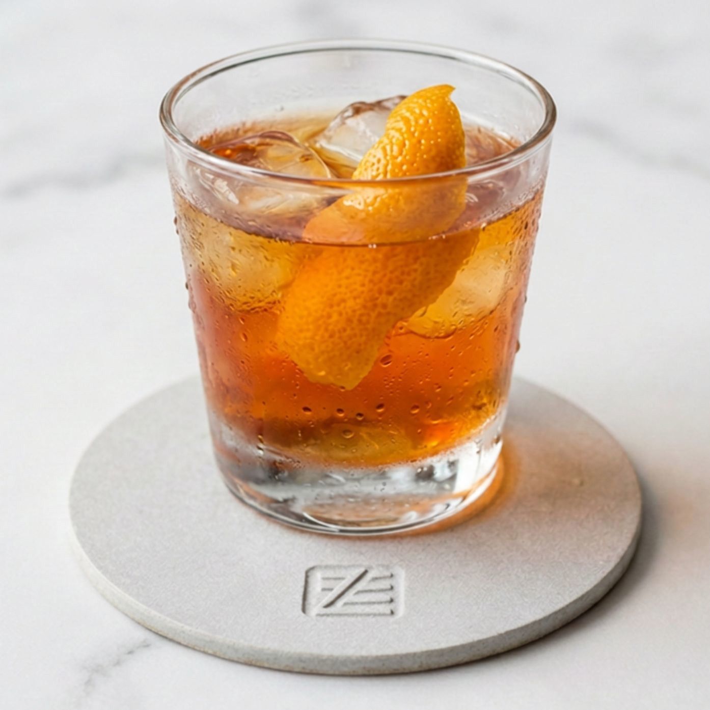 Sweating cocktail glass on a gray absorbent diatomaceous earth coaster resting on a marble surface.