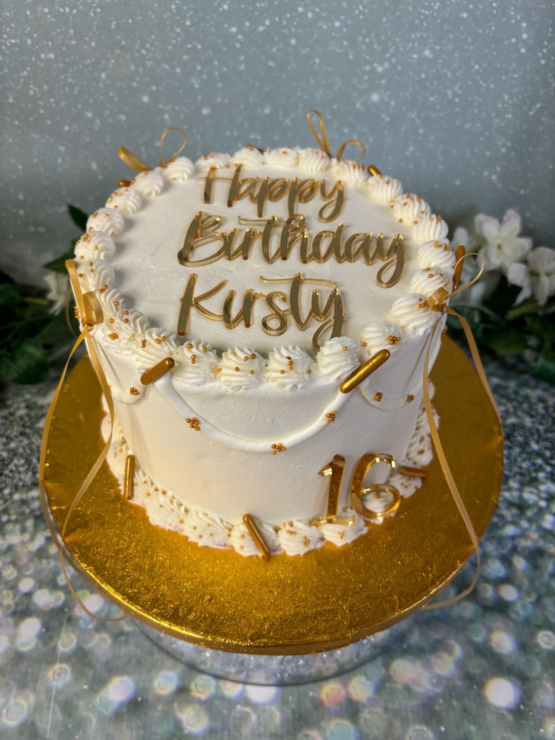 Cream Round Cake With gold Acrylic Toppers, Bows And Sprinkles