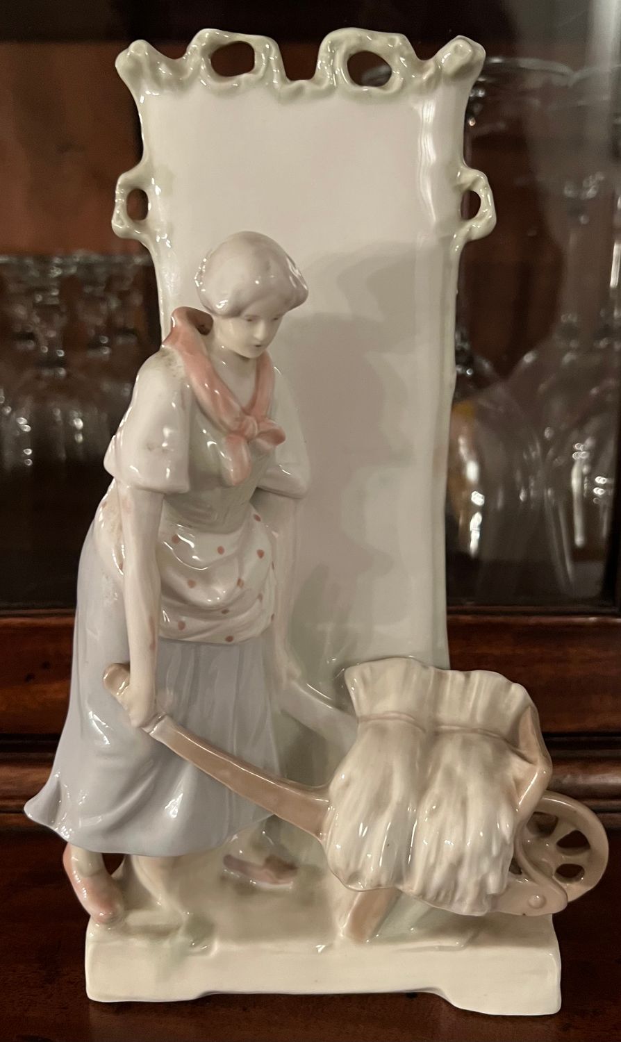Porcelain vase with figurine of a farmer's wife with a wheelbarrow Porcelain vase with figurine of a farmer's wife with a wheelbarrow