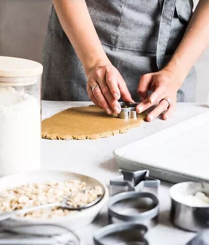 Baker shaping cookies from flattened dough using cookie cutters
