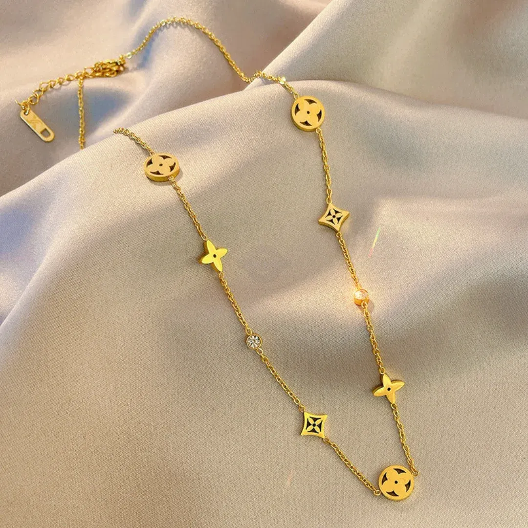 Gold necklace featuring four-leaf clover and four-point star with gem