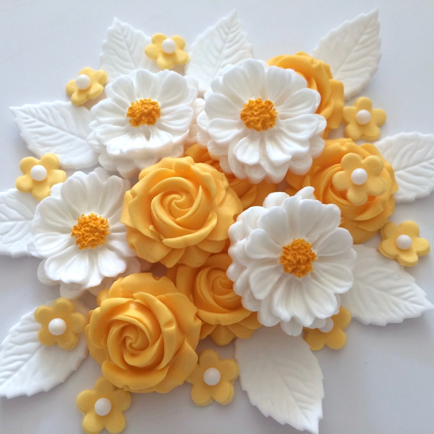 Apricot coloured roses, large hand-painted white daisy style flowers, small apricot coloured flowers with white sugar pearl centres, white leaves.