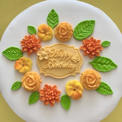 Apricot coloured Happy Birthday plaque with roses, dahlias, violas, green leaves.