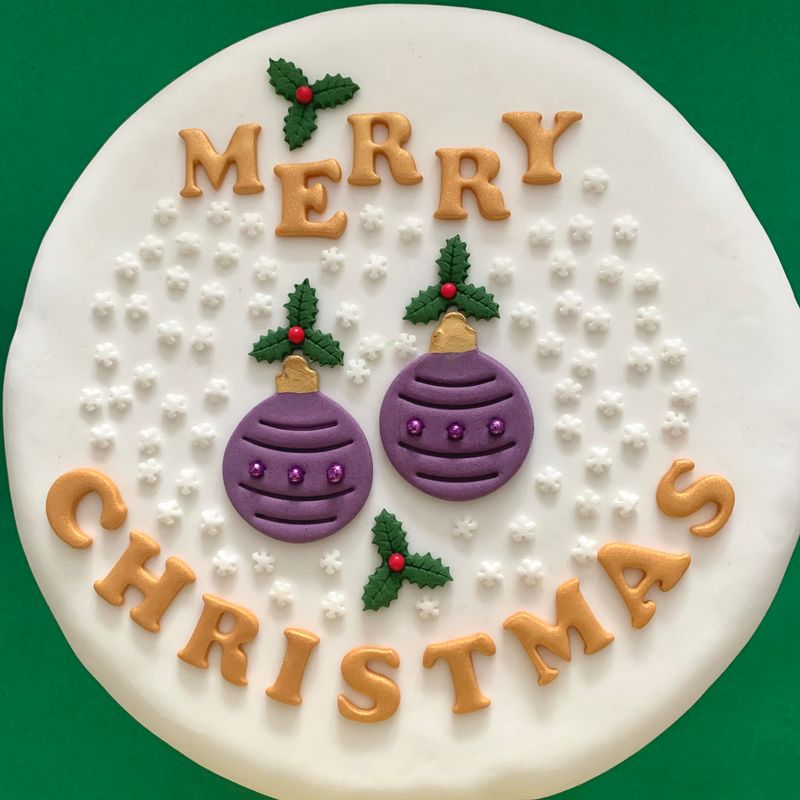 Gold merry Christmas letters, two purple baubles and holly fondant cake decorations