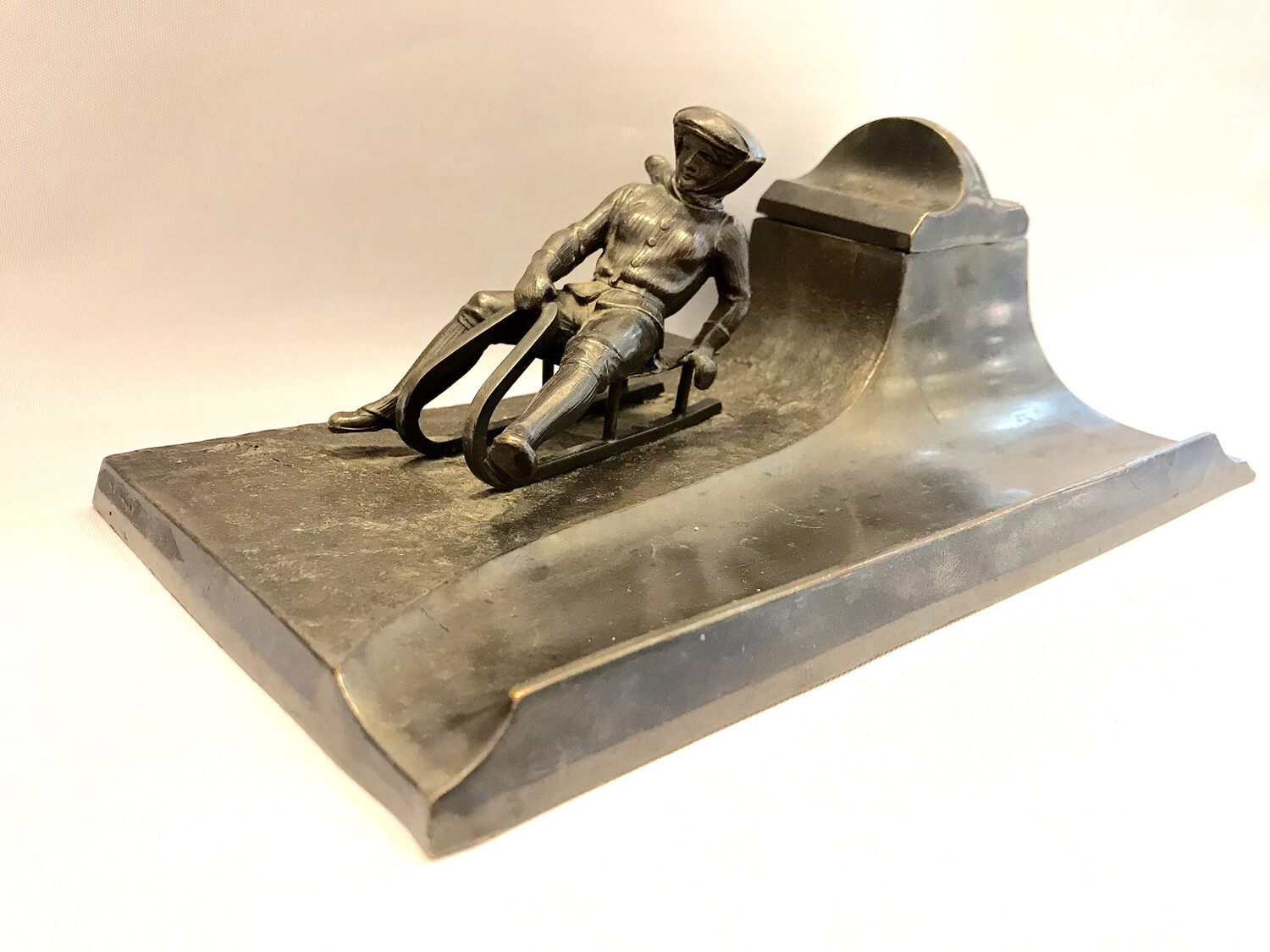Tintenfass mit Glas dekoriert mit Skulptur einer Rodlerin auf Schlitten um 1900 mit Stiftablage brüniertens Metall