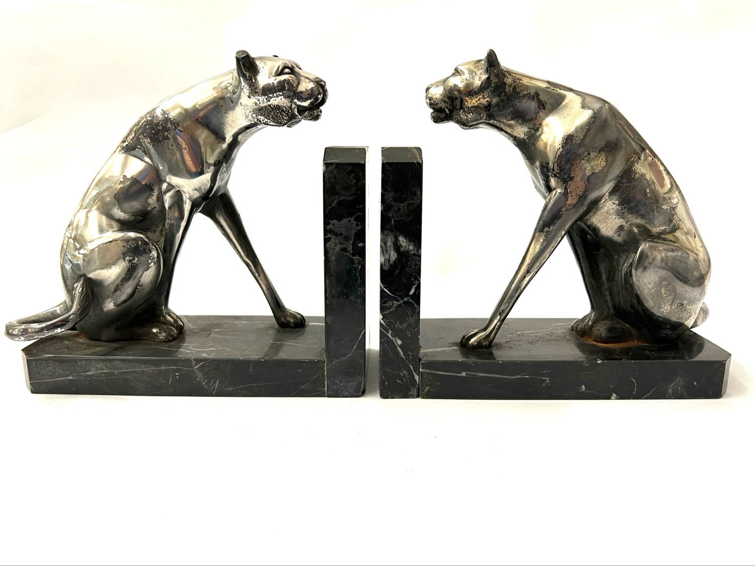 A rare pair of Art Deco panther-shaped bookends, circa 1925, made of nickel-plated metal on marble bases. The metal is heavily worn, and one ear is damaged.