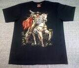 T-Shirt - XL - Un Cavalier Cow Boy sur son Cheval Blanc avec sa Cape Rouge, et Pointe son Revolver galope sur la Route de Crânes du village.