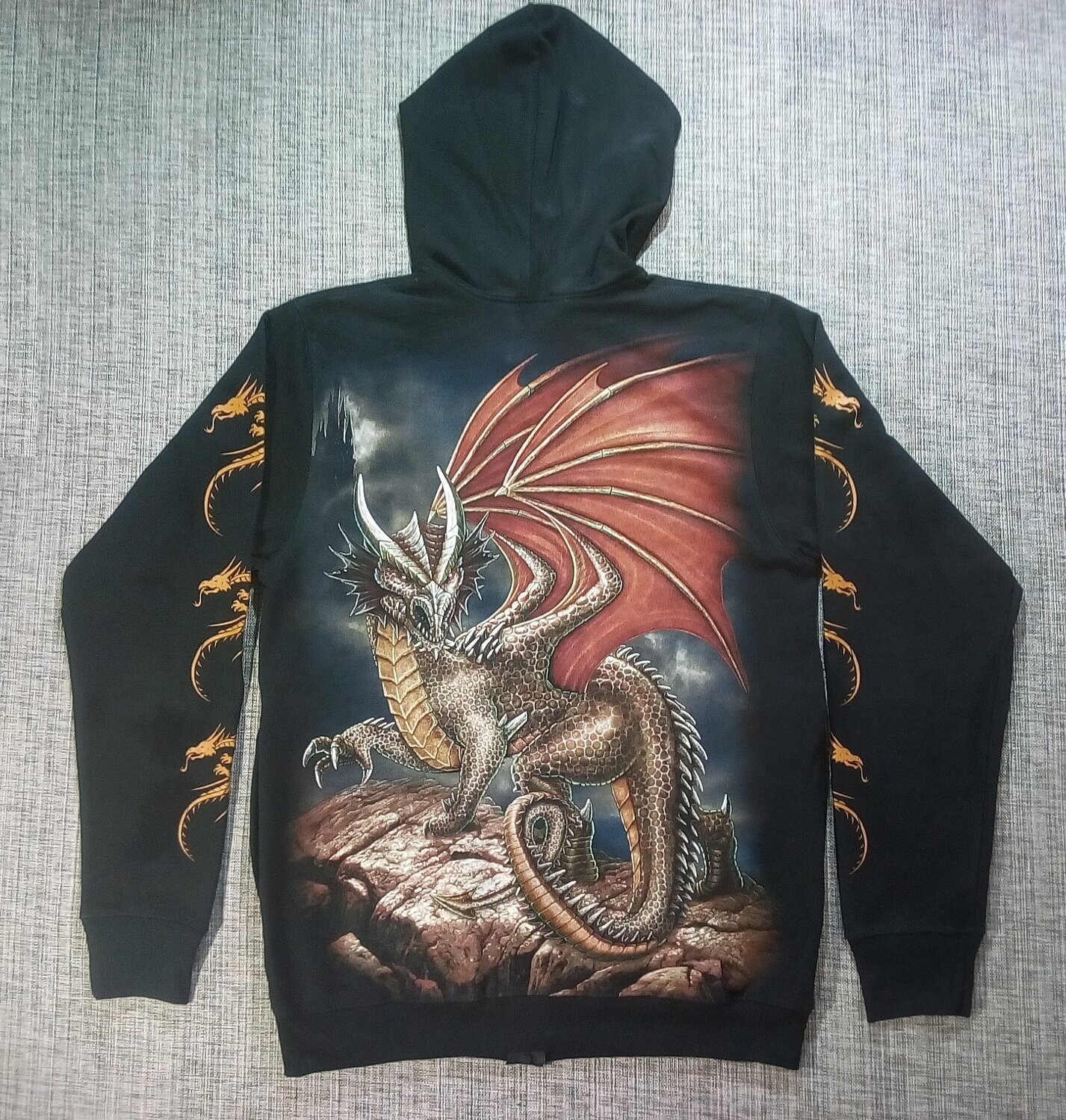 Un Sweat de Taille 46/48, Représente un "Dragon Marron avec sa Paire d'Aile Rouille Posé sur une Montagne, au Fond un Château dans la Prune.