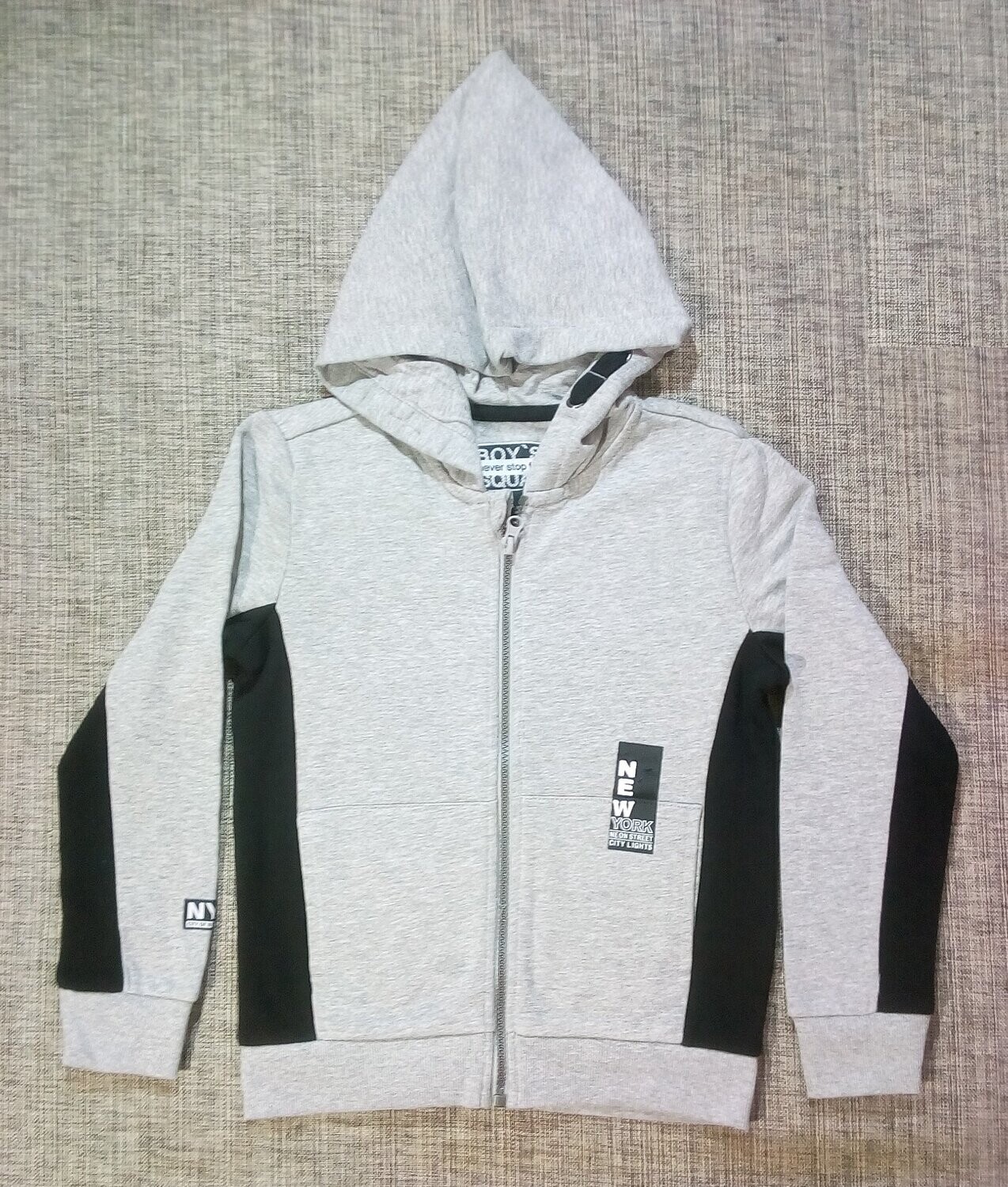 Un Sweat "Gris", de Taille 38/40, avec des Bande Noir à la "Vertical" en Couleur Unique, un Logo Côté Poche Gauche de "New York..." et sur Manche Droite.