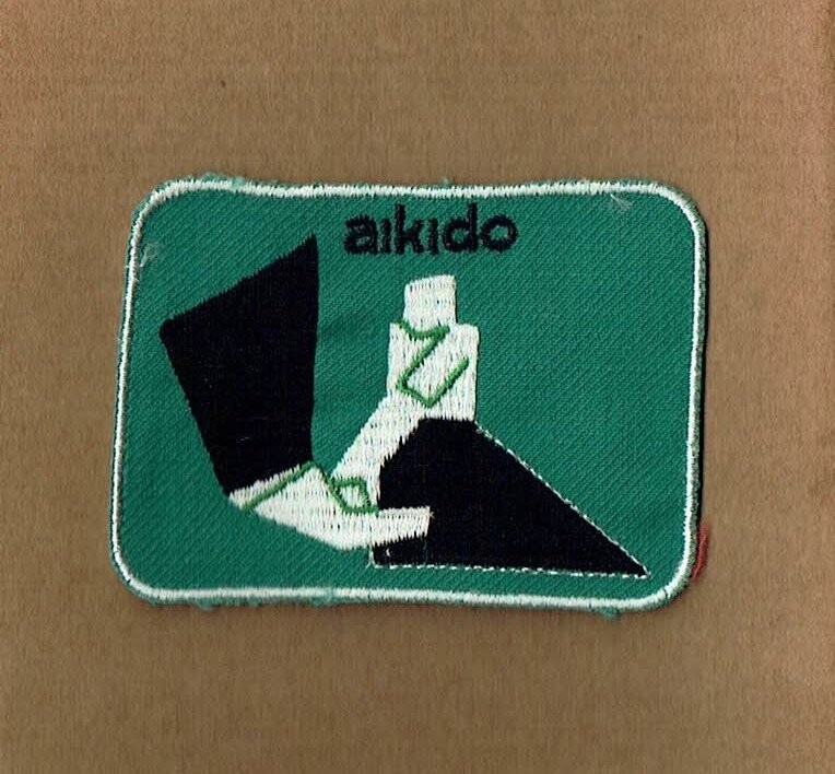 Patch/Écusson Broderie à Coudre - Mouvement d'une Prise d'Aïkido sous un Fond Vert avec un Contour Blanc, Dimension  9 x 6.5 cm