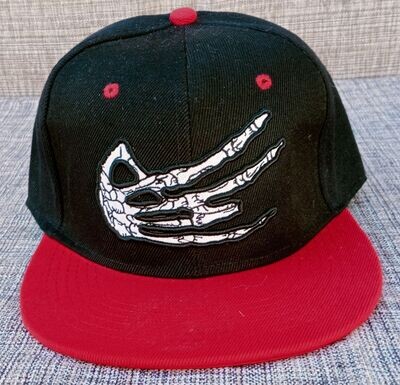 Une Casquette Noir avec une Broderie "Main Squelette Blanc" et sa Visière Rouge, de Style "Hit Hot" Broderie à l'Arrière.