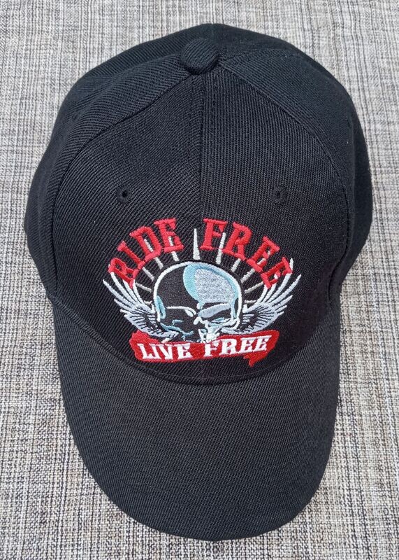 Une Casquette Noir avec une Broderie Une Casquette Noir avec une Broderie "Crâne en Bleu/Blanc, Paire d'Aile Blanc" et en Rouge/Blanc "Ride Free, Live Free" et sa Visière Noire Bombée
