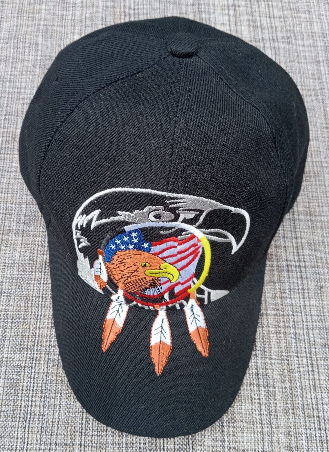 Une Casquette Noir avec une Broderie "2 Portraits Aigles, dessus un Drapeau Américain entouré d'un Capteur de Rêve à 3 Plumes"