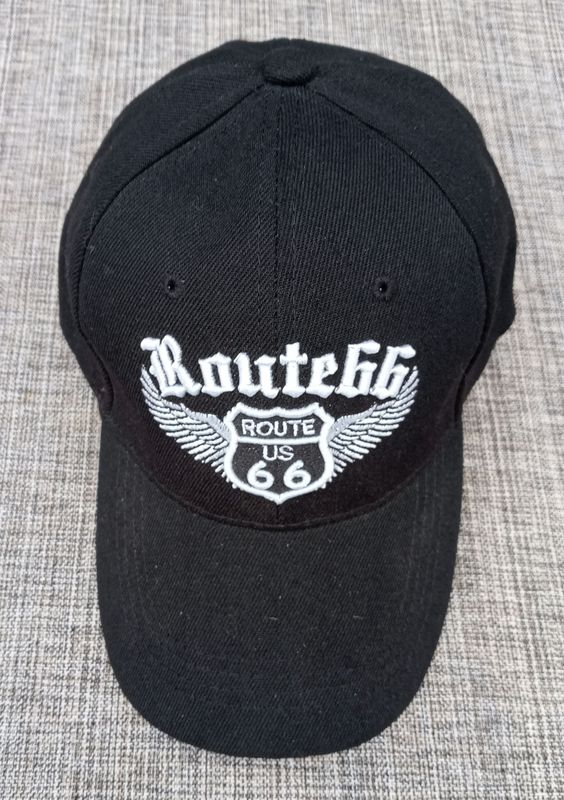 Une Casquette Noir avec une Broderie "Bouclier Route US 66, Route 66 Paire d'Aile en Blanc", et sa Visière Noire Bombée