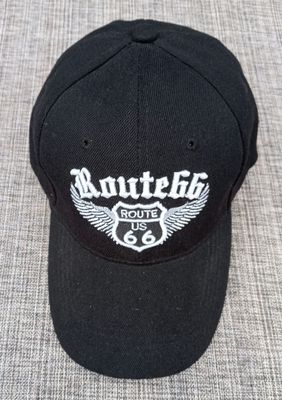 Une Casquette Noir avec une Broderie "Bouclier Route US 66, Route 66 Paire d'Aile en Blanc", et sa Visière Noire Bombée
