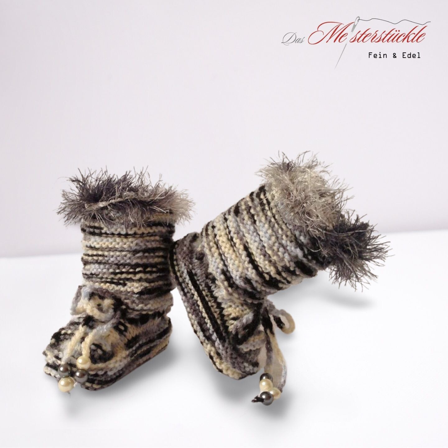 handgestrickte Babystiefel schwarz weiß mit Fransen
