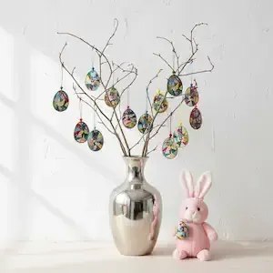 Handmade colorful confetti eggs decoratively arranged on branches in a silver vase
