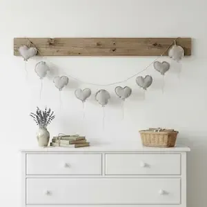 Hanging garland with heart and fabric balloons above country-style chest of drawers