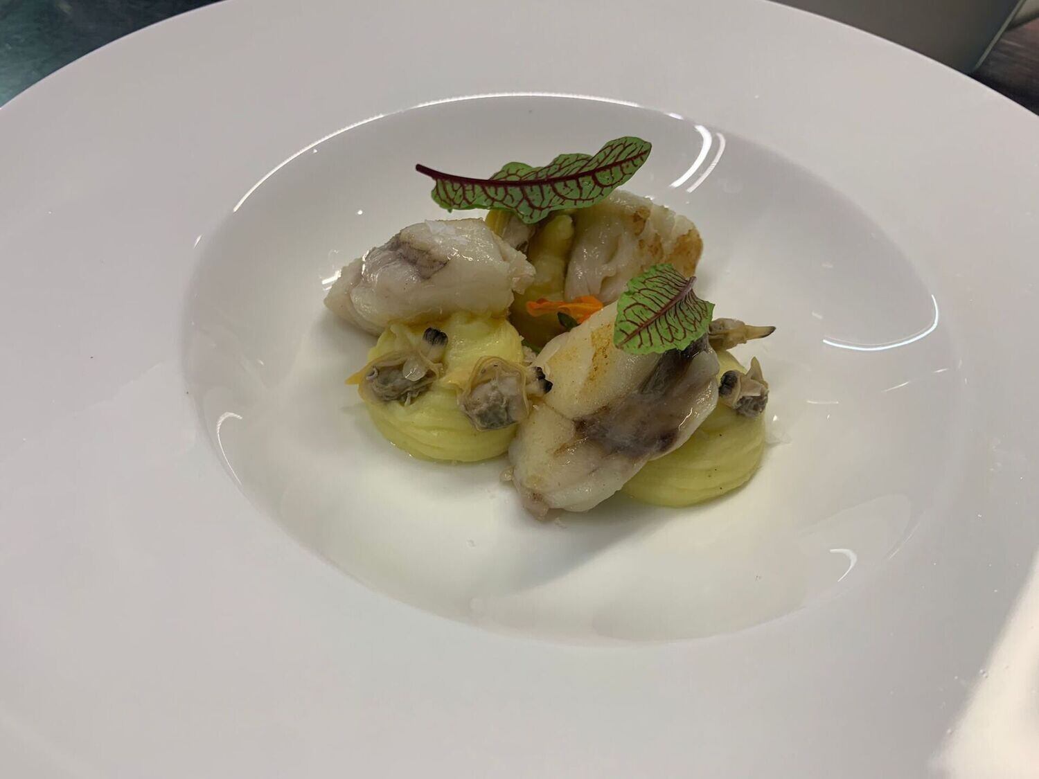 Guancia di rana pescatrice in brodetto di vongole veraci,  limoni fermentati e  spinaci novelli