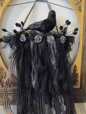 Halloween black crow perched on a branch with ornate garland wall or door decoration Halloween black crow perched on a branch with ornate garland wall or door decoration