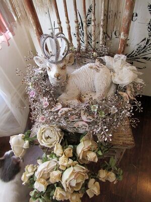 White lamb statue with handmade crown set in a basket with nesting and garland