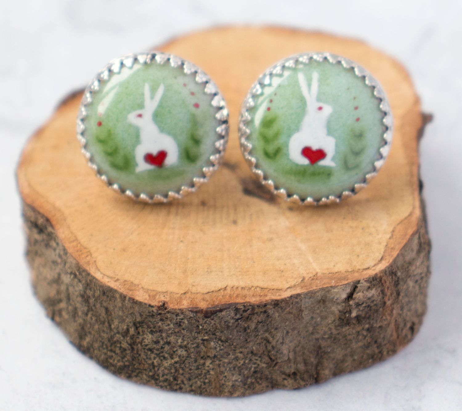Sterling silver earrings featuring a white rabbit with a red-heart tail on a green enamelled background.