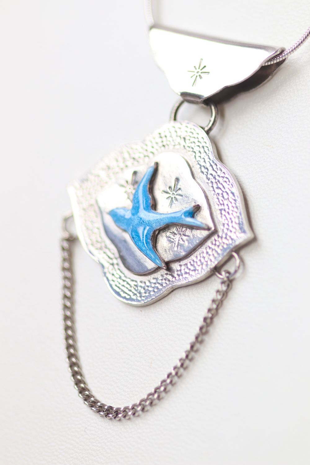 Sterling silver and blue enamel swallow on a textured silver background