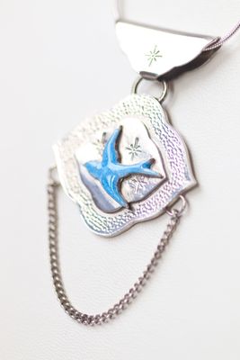 Sterling silver and blue enamel swallow on a textured silver background