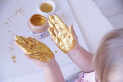 Child exploring metallic MUCKI finger paint with hands