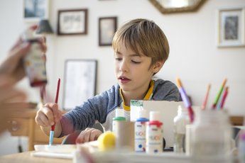 Child painting with MUCKI craft paints at a table