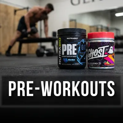 Two pre-workout supplement containers on a gym floor with a blurred athlete training in the background.