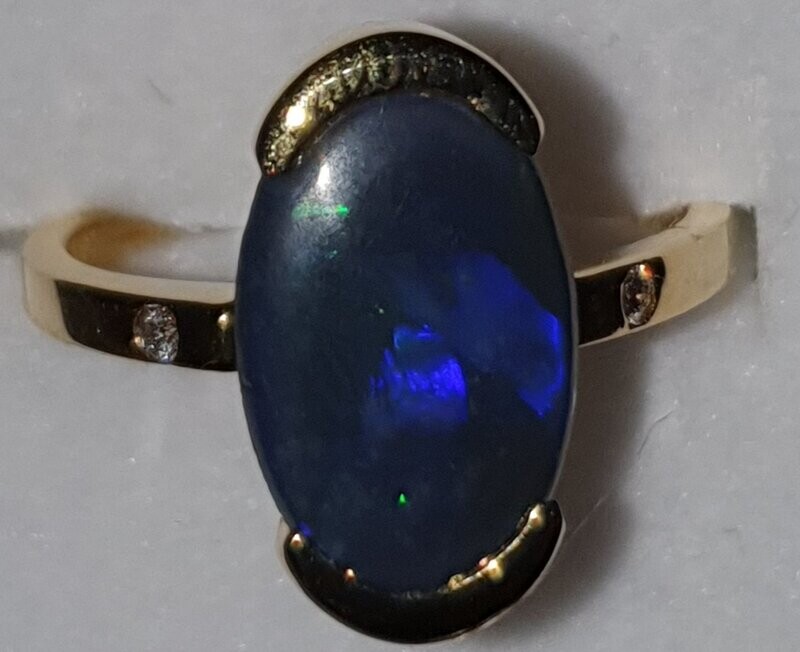 R18 Black Opal & Diamond Ring, Featuring Lightning Ridge Black Solid Opal Cabochon, Set in 9ct Gold With Diamond Shoulders. Predominant Purple and Green Flashing Colours R18 Black Opal & Diamond Ring, Featuring Lightning Ridge Black Solid Opal Cabochon, Set in 9ct Gold With Diamond Shoulders. Predominant Purple and Green Flashing Colours