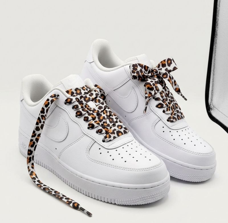 Lacets satinés imprimé léopard léopard marron et noir montés sur baskets Nike Air Force 1 blanches.