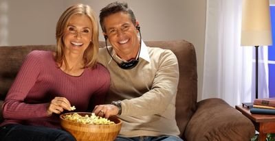 Man wearing TV Listening system headset while he and his wife eat popcorn.