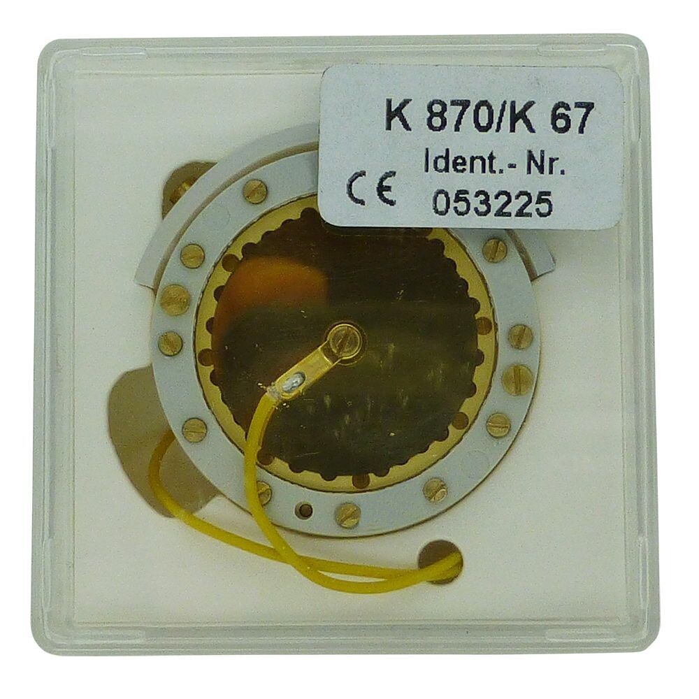 Neumann plastic box containg round capsule K870 with two yellow wires and lots of screws around a white circumference