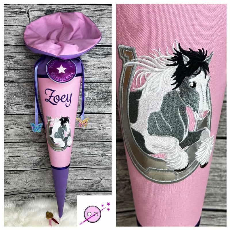 Pferd im Huseisen Schultüte rosa aus Stoff individuell mit Namen für Mädchen. Ein aufwendig gesticktes Motiv mit einem Pferd, welches durch ein Hufeisen springt Das Pferd ist weiß grau auf rosa Hintergrund. Die Spitze und der Verschluss sind lila.