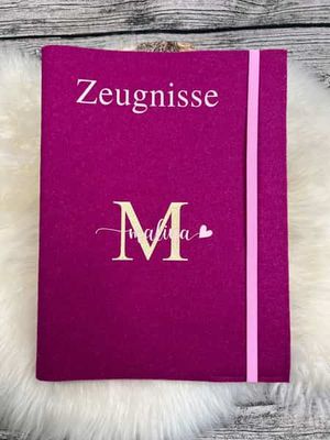 Eine Zeugnismappe aus Filz, bestickt mit einem großen Anfangsbuchstaben und den Namen darin.
