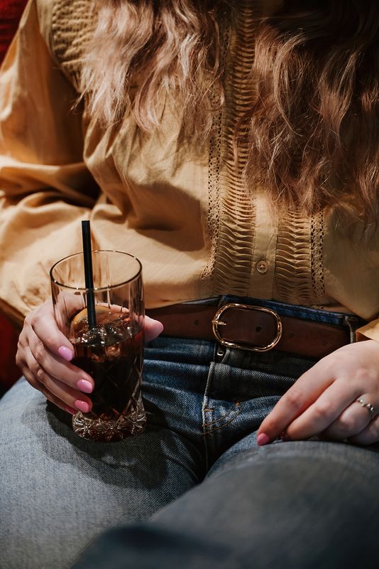 The Daily vrouwenriem in donkerbruin, gedragen op een jeansbroek en okerkleurige bloes.