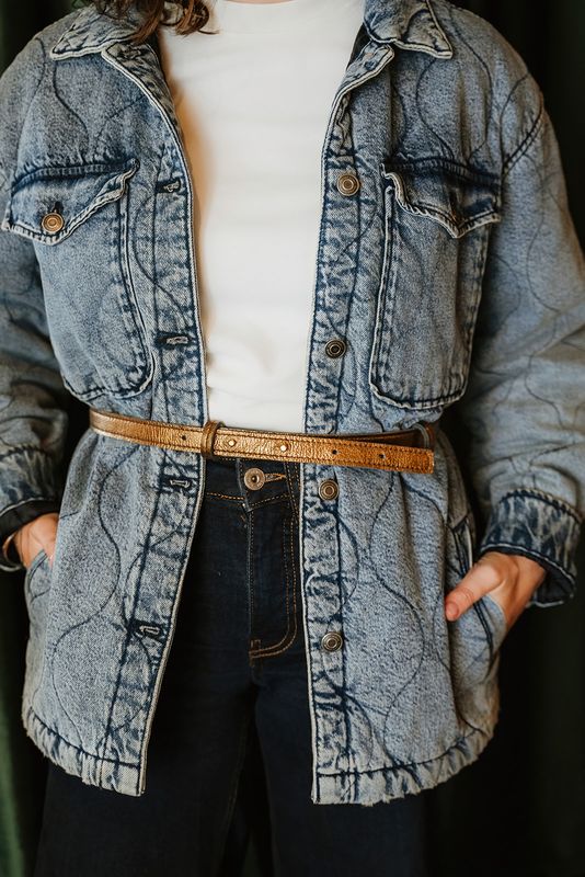 Vrouw draagt handgemaakte metallic leren tailleriem Blinding Beauty van Atelier Loulou over denim
