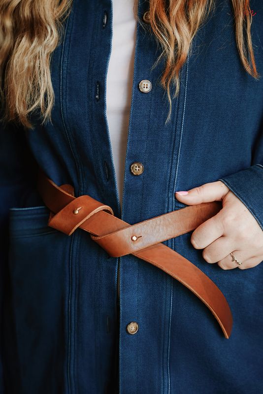 Vrouw draagt handgemaakte cognac leren tailleriem Knotorious over denim jas, Atelier Loulou