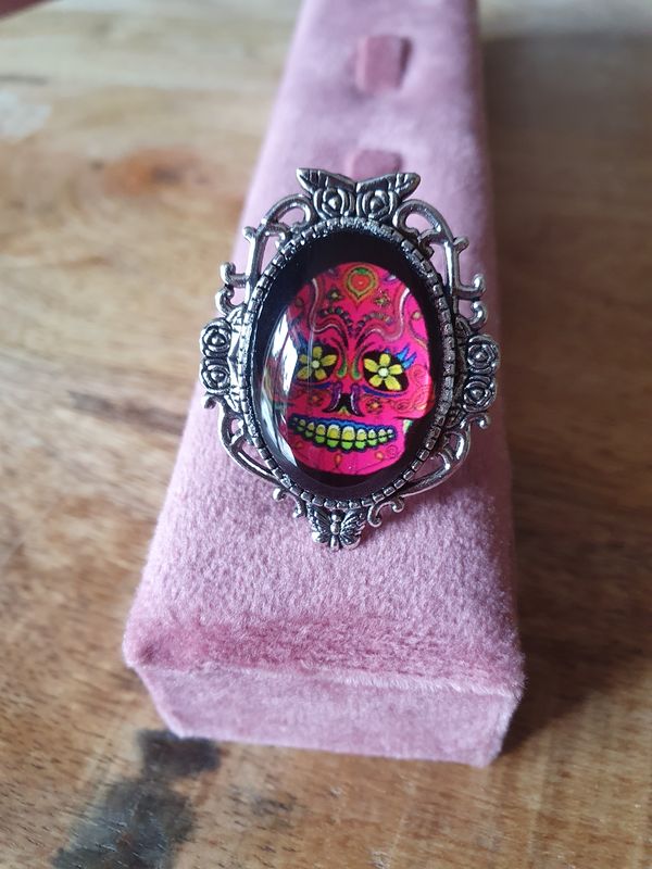 💐 Bague ovale fantaisie ajustable tête de mort fleurie, fuchsia et jaune. Symbole de la culture mexicaine. Acier inoxydable ciselé. Modèle unique.